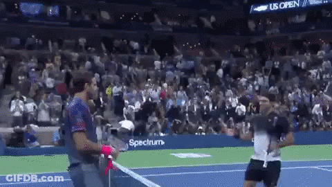 A Man Holding A Tennis Racquet On A Tennis Court In Front Of A Crowd Sponsored By Spectrum GIF