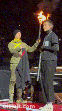 A Man Holding A Torch Stands Next To A Woman Holding A Jacket GIF
