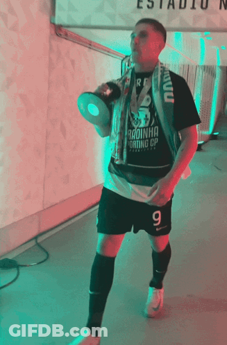 A Man Holding A Trophy And Wearing A Shirt That Says " Radinha " GIF