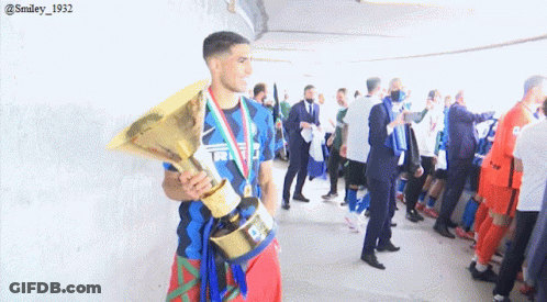 A Man Holding A Trophy In A Locker Room With A Smiley 1932 Watermark GIF