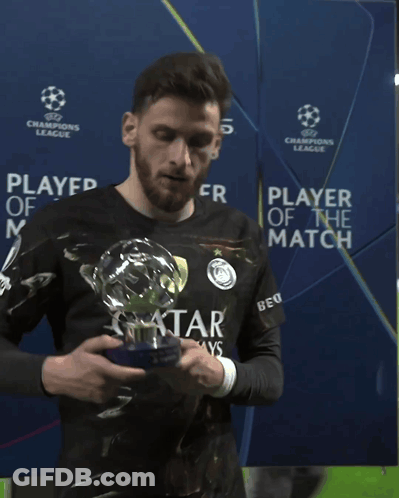 A Man Holding A Trophy In Front Of A Champions League Banner GIF