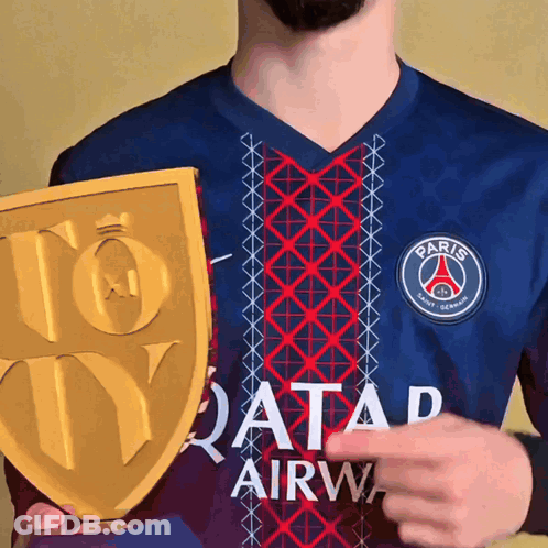 A Man Holding A Trophy In Front Of A Shirt That Says Qatar Airway GIF