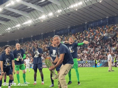 A Man Holding A Trophy On A Soccer Field With Players Wearing Shirts That Say Winners GIF