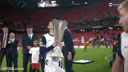 A Man Holding A Trophy On A Soccer Field With Tnt Sports On The Bottom Right GIF