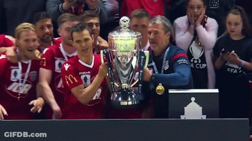 A Man Holding A Trophy With A Mcdonald 'S Logo On It GIF