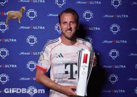 A Man Holding A Trophy With The Letter T On His Shirt GIF