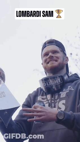 A Man Holding A Trophy With The Name Lombardi Sam On The Bottom GIF