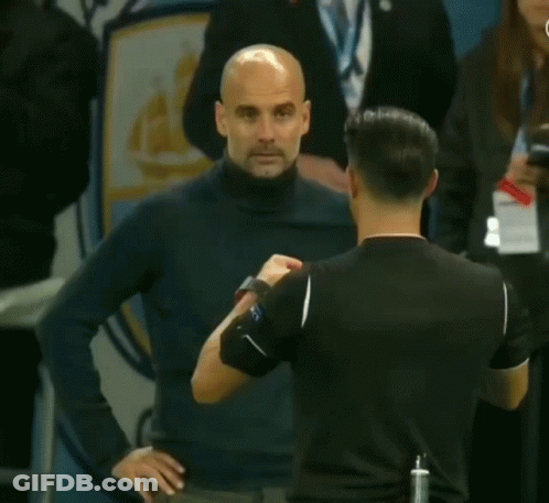 A Man Holding A Yellow Card In Front Of An Anchester Logo GIF