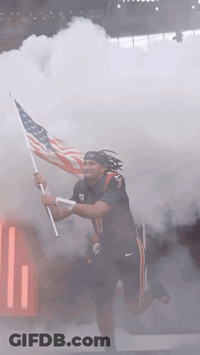 A Man Holding An American Flag With The Number 10 On His Jersey GIF