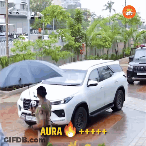 A Man Holding An Umbrella In Front Of A Car That Says Aura On The Bottom GIF