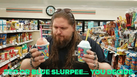 A Man Holding Two Cups Of Slurpee In A Convenience Store GIF