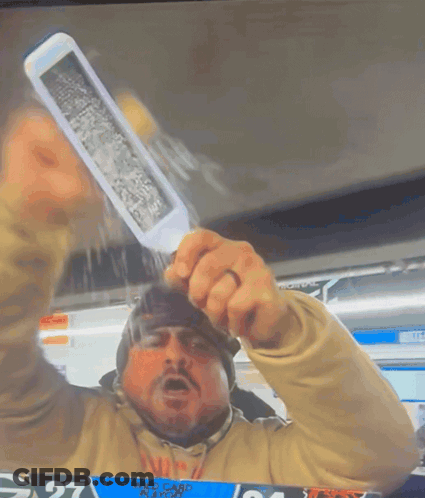 A Man Holding Up A Knife In Front Of A Scoreboard With The Number 27 On It GIF