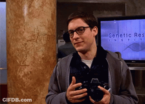 A Man Holds A Camera In Front Of A Screen That Says Genetic Research GIF