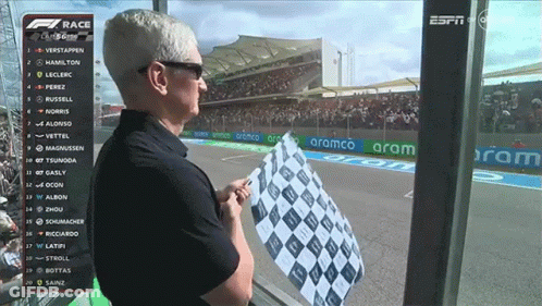 A Man Holds A Checkered Flag In Front Of A Screen That Says Espn On It GIF
