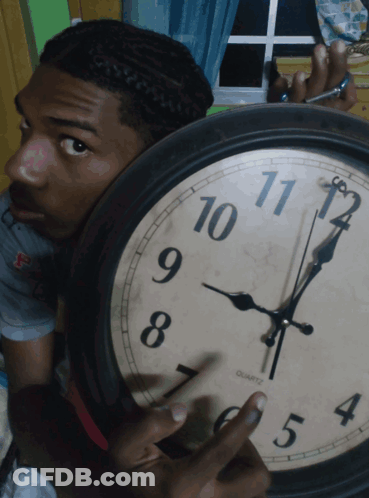 A Man Holds A Clock That Says Quartz On The Face GIF