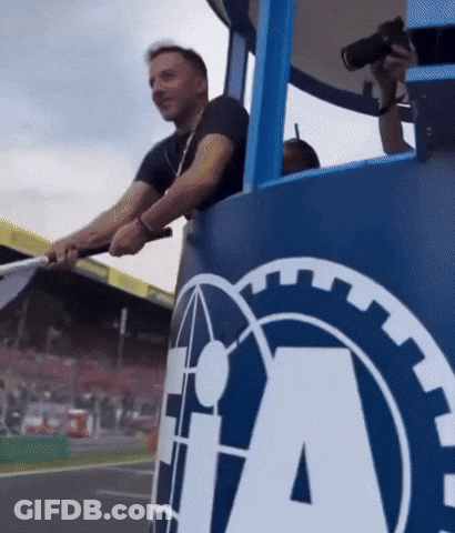 A Man Holds A Flag In Front Of A Large Ia Logo GIF