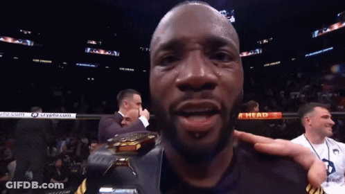 A Man Holds A Trophy In Front Of A Sign That Says " Ahead " GIF
