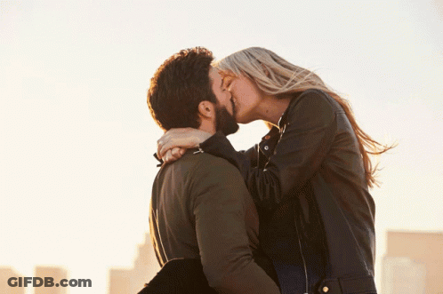 A Man Holds A Woman In His Arms And They Kiss GIF