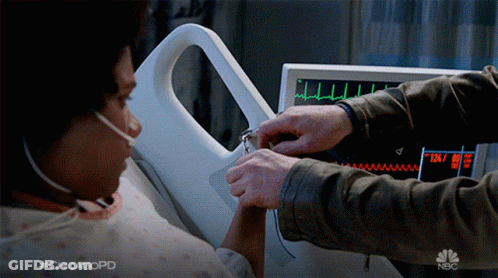 A Man Holds A Woman 'S Hand In Front Of A Monitor That Says Nbc GIF