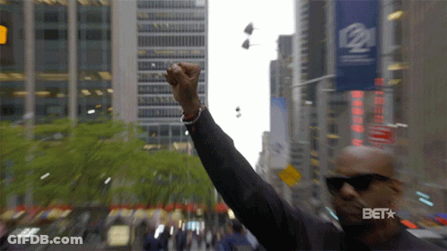 A Man Holds His Fist Up In The Air In Front Of A Sign That Says Bet GIF