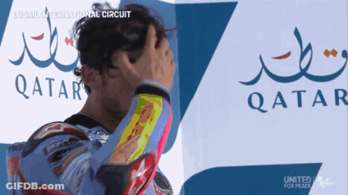 A Man Holds His Head In Front Of A Qatar Logo GIF
