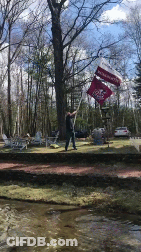 A Man Holds Up A Flag That Says Massachusetts On It GIF