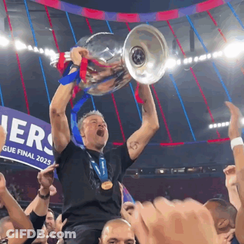A Man Holds Up A Trophy In Front Of A Banner That Says ' League Final 2025 ' GIF