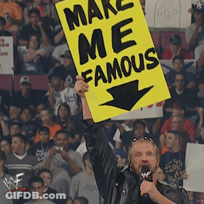 A Man Holds Up A Yellow Sign That Says Make Me Famous GIF