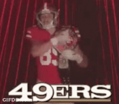 A Man In A 49Ers Jersey Is Standing In Front Of A Red Curtain GIF