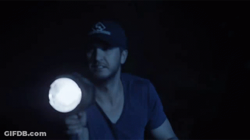 A Man In A Baseball Cap Holds A Flashlight GIF