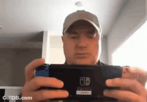A Man In A Baseball Cap Is Holding A Nintendo Switch In His Hands GIF