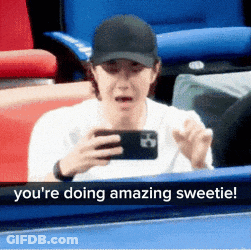 A Man In A Baseball Cap Is Looking At His Phone And Says " You 'Re Doing Amazing Sweetie ! " GIF