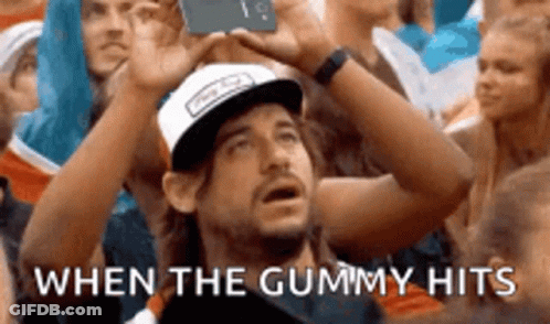 A Man In A Baseball Cap Is Taking A Picture Of A Crowd Of People . GIF
