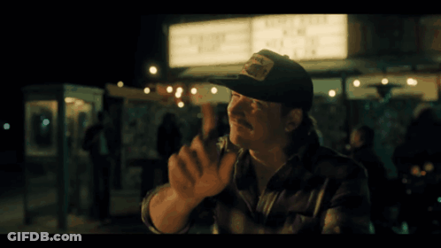 A Man In A Baseball Cap Stands In Front Of A Sign That Says ' Live Free ' GIF