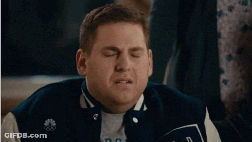 A Man In A Baseball Jacket Is Making A Funny Face . GIF