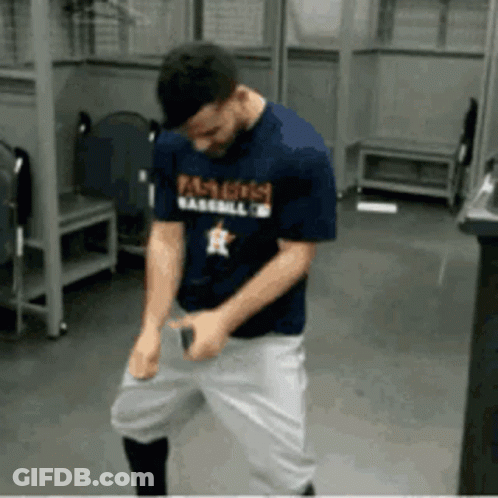 A Man In A Baseball Uniform Is Dancing In A Locker Room GIF