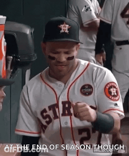A Man In A Baseball Uniform Is Sitting In A Dugout . GIF