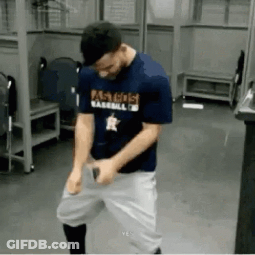 A Man In A Baseball Uniform Is Standing In A Locker Room With His Hands On His Hips . GIF