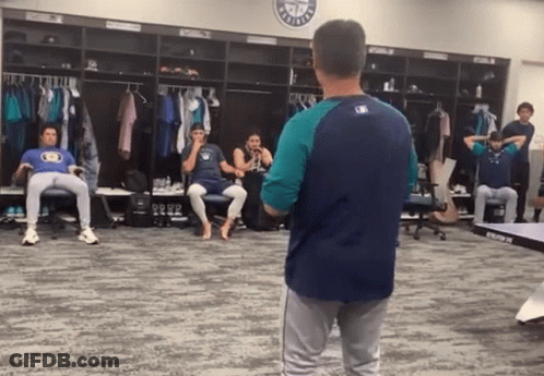 A Man In A Baseball Uniform Stands In A Locker Room With A Mlb Logo On The Wall GIF