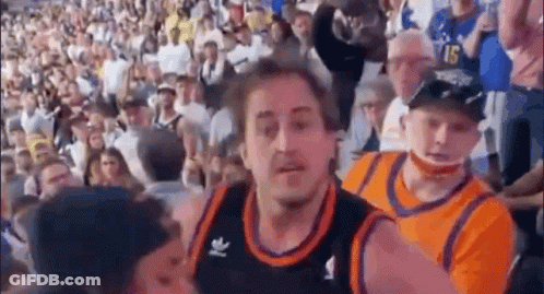 A Man In A Basketball Jersey Is Standing In Front Of A Crowd Of People In A Stadium . GIF