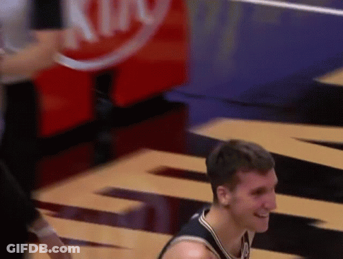A Man In A Basketball Uniform Is Smiling In Front Of A Sign That Says King GIF