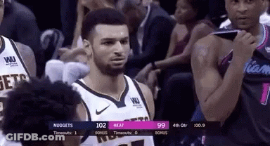 A Man In A Basketball Uniform Is Standing In Front Of A Crowd During A Basketball Game . GIF