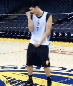 A Man In A Basketball Uniform Is Standing On A Court With His Hands In His Pockets . GIF