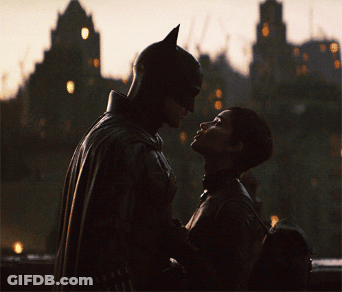 A Man In A Bat Suit And A Woman In A Catsuit Are Looking Into Each Other 'S Eyes GIF