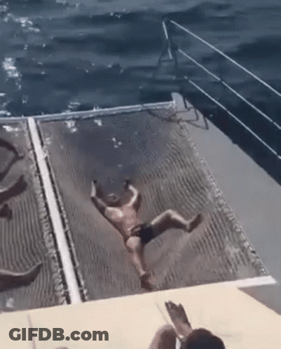 A Man In A Bathing Suit Is Falling Into The Ocean From A Boat . GIF