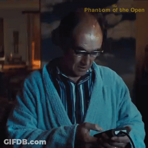 A Man In A Bathrobe Is Playing A Video Game With The Phantom Of The Open Written In The Corner GIF
