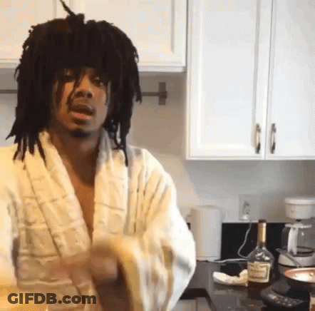 A Man In A Bathrobe Is Standing In A Kitchen With A Bottle Of Hennessy On The Counter GIF