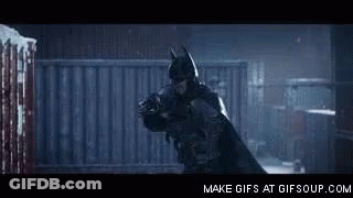 A Man In A Batman Costume Is Holding Another Man In A Dark Room . GIF