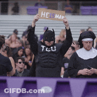 A Man In A Batman Costume Is Holding Up A Sign That Says Heisman GIF