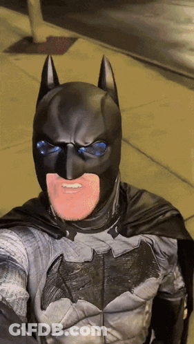 A Man In A Batman Costume Is Smiling GIF